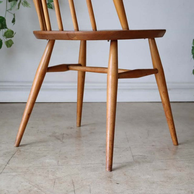 Mid-century British vintage Ercol Goldsmith dining chair in teak with spindle backrest and tapered legs, smooth wood grain.