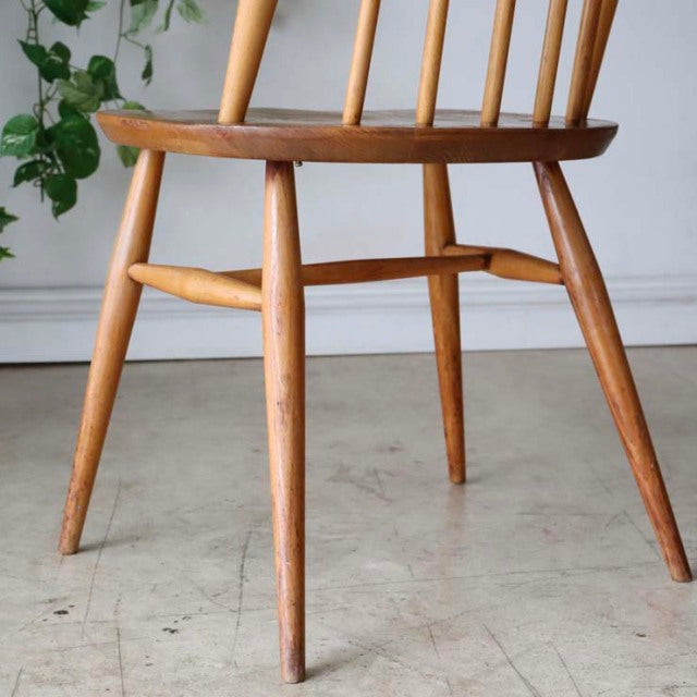 Vintage mid-century British Ercol dining chair in teak with spindle backrest and tapered legs, smooth wood grain visible.