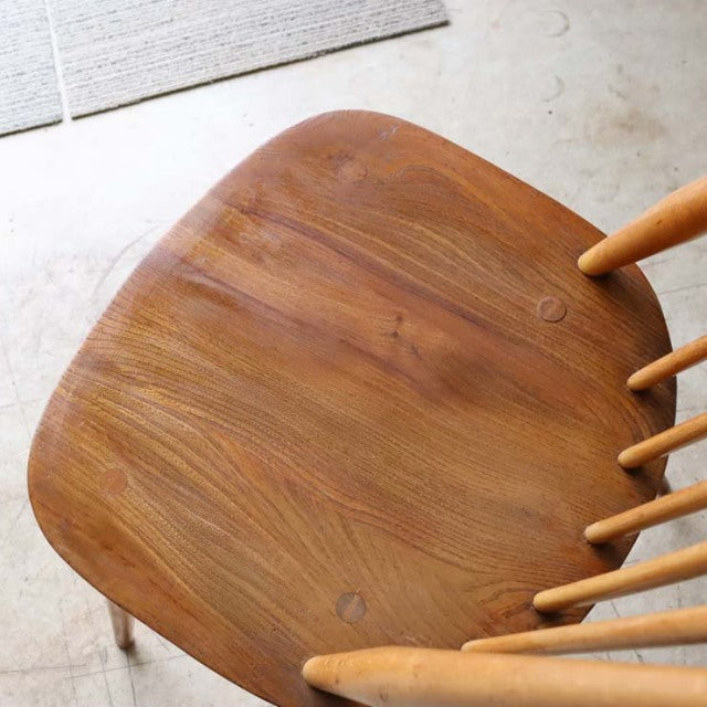 Vintage British mid-century teak dining chair seat with smooth wood grain and spindle backrest legs visible.