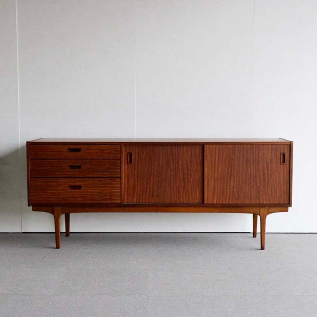 Mid-century British teak sideboard by Nathan with clean lines, three drawers, sliding doors, and slender tapered legs.