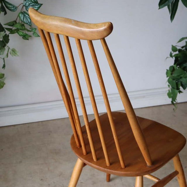 Vintage British mid-century Ercol Goldsmith dining chair in warm teak with curved top rail and slender spindle backrest.