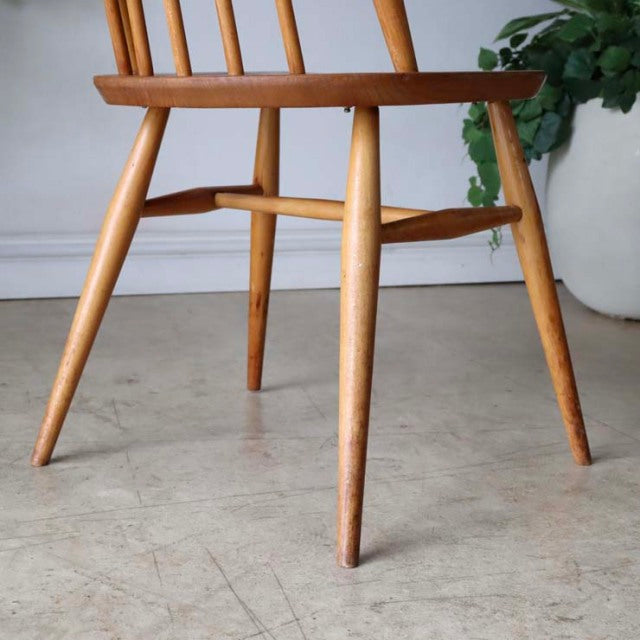 Mid-century British Ercol dining chair in teak with sleek tapered legs and visible wood grain.