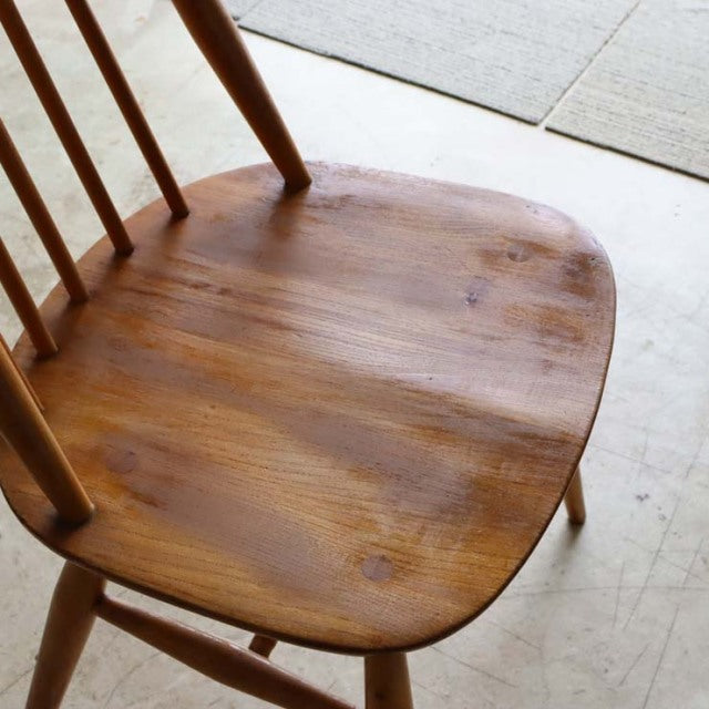 Vintage mid-century British Ercol dining chair in teak with smooth rounded seat and slender spindle backrest.