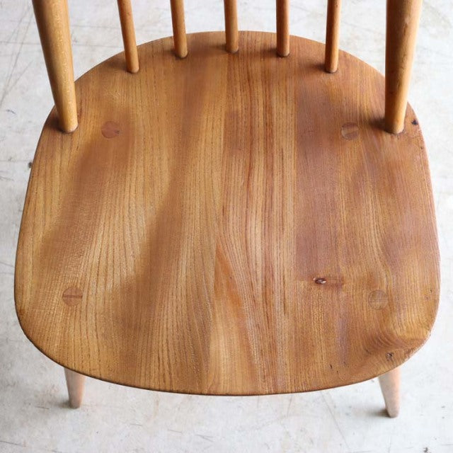 Vintage British mid-century Ercol dining chair seat in warm teak with smooth wood grain and spindle back legs visible.