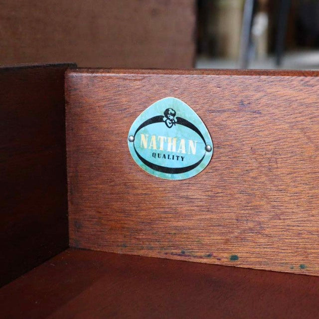Close-up of teak wood grain and Nathan brand label inside vintage mid-century British sideboard from Denmark.