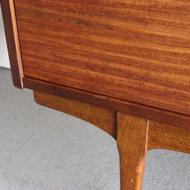 Close-up of vintage teak mid-century British sideboard leg with smooth wood grain and curved detailing from Nathan furniture.