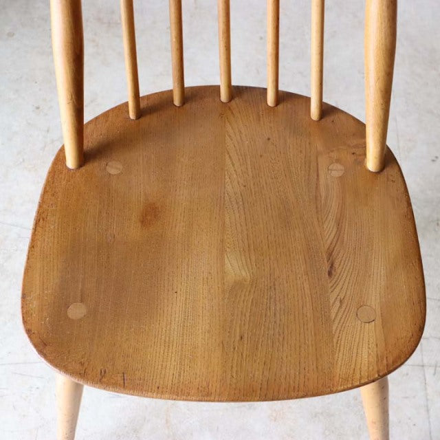Vintage mid-century British Ercol Goldsmith high-back chair in natural teak with smooth wood grain and slender spindle legs.