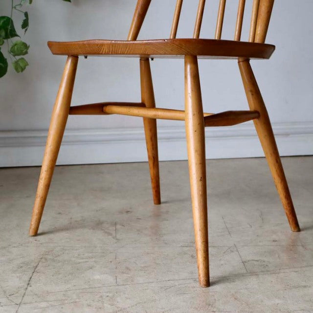 Mid-century British Ercol Goldsmith high-back chair in natural teak with visible wood grain and tapered legs.