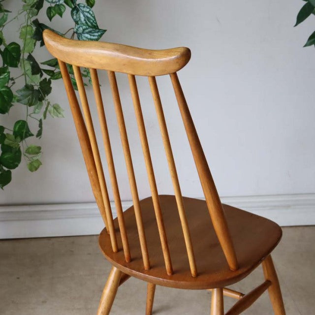 Mid-century British Ercol Goldsmith high-back dining chair in natural teak with spindle backrest and tapered legs.