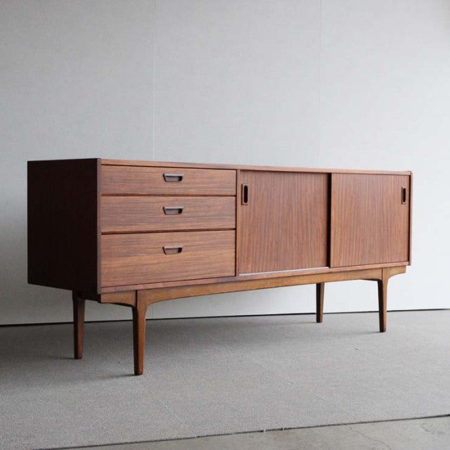 Mid-century British vintage teak sideboard by Nathan with clean lines, three drawers, sliding doors, tapered legs, and.