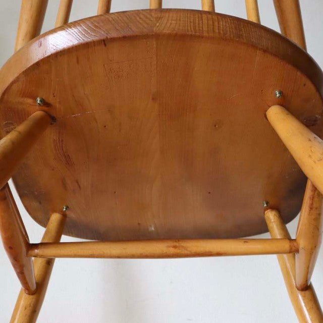 Vintage teak Ercol Goldsmith mid-century British high-back chair with natural wood grain and slender legs viewed from below.