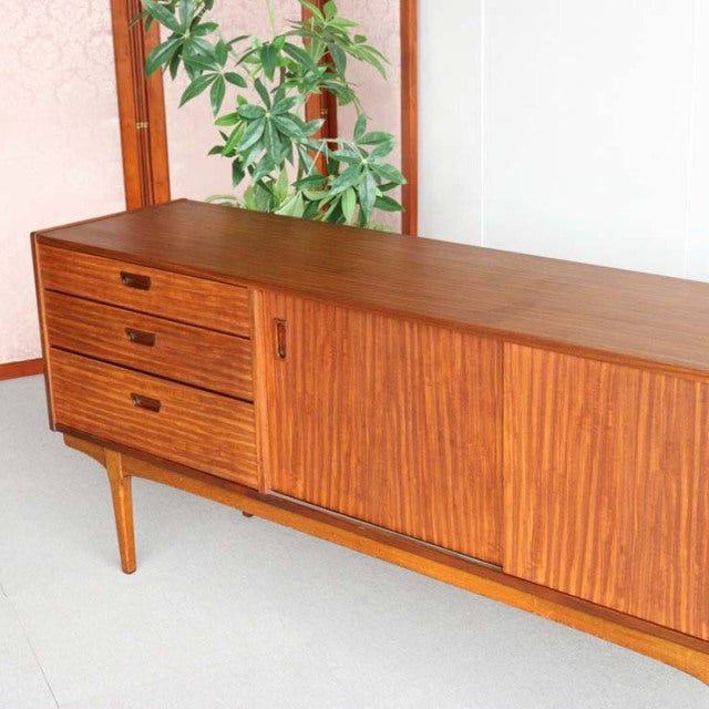 Mid-century British vintage teak sideboard by Nathan with rich wood grain, tapered legs, sliding door, and three drawers.