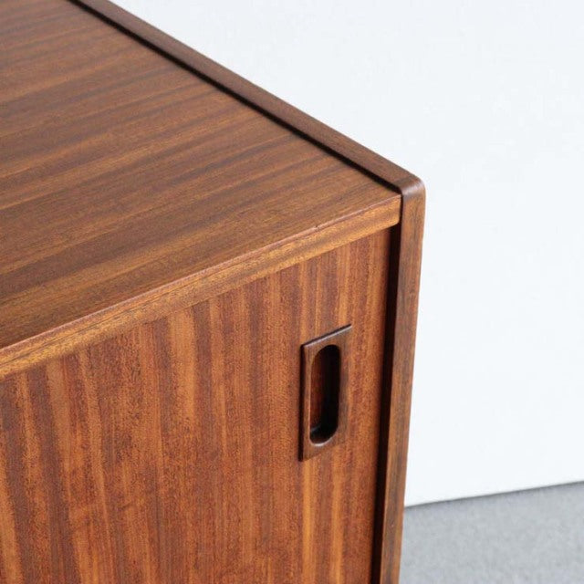 Close-up of vintage teak sideboard corner by British brand Nathan, showing smooth wood grain and recessed handle detail.
