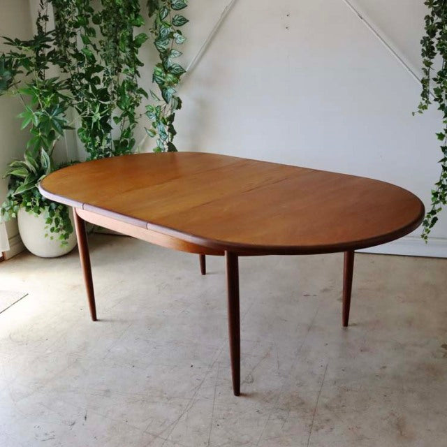 Oval vintage teak dining table by G-Plan with smooth wood grain, slender tapered British mid-century legs, classic Danish.