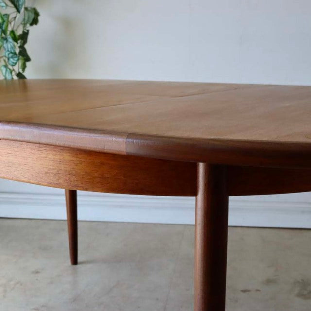Vintage teak G-Plan mid-century British dining table with oval top and tapered round legs.