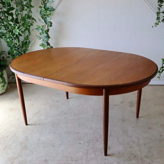 Oval vintage teak dining table by G-Plan with smooth wood grain, slender tapered legs, British mid-century design.
