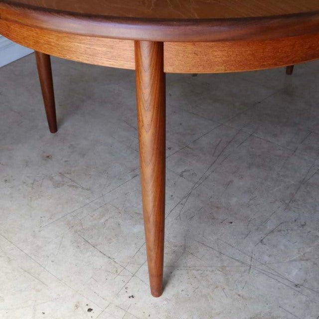 Oval vintage teak dining table with slender tapered legs showcasing British mid-century design influences from Denmark.