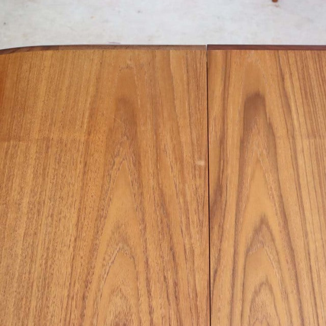 Mid-century British vintage teak dining table top with smooth oval shape and visible wood grain patterns.