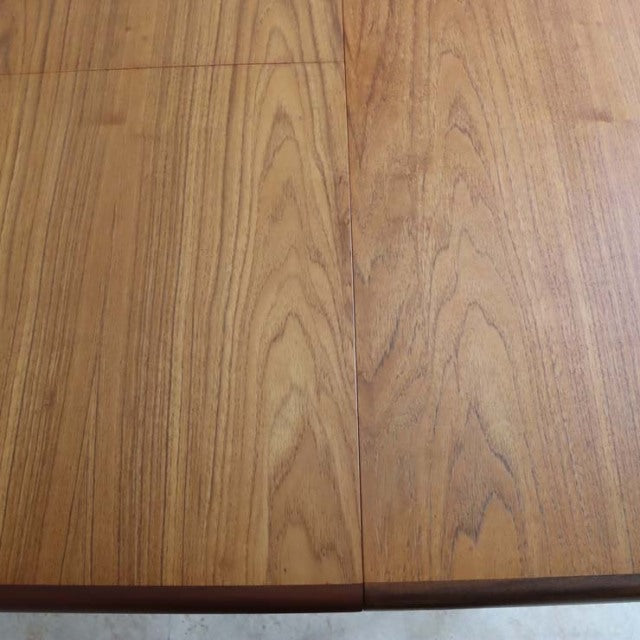 Close-up of vintage British G-Plan teak dining table top showing smooth oval shape and rich mid-century wood grain.