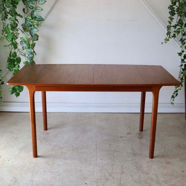 Vintage British mid-century teak dining table by McIntosh with smooth rectangular top and rounded legs, showcasing rich wood .