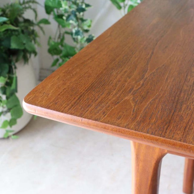Mid-century British vintage teak dining table by McIntosh with smooth wood grain and sturdy angled legs.