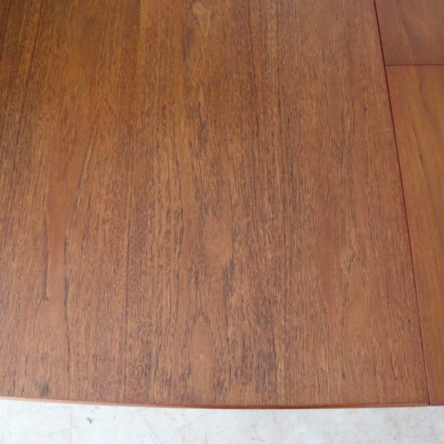 Close-up of vintage teak wood dining table top showing rich grain and smooth finish, British mid-century style.
