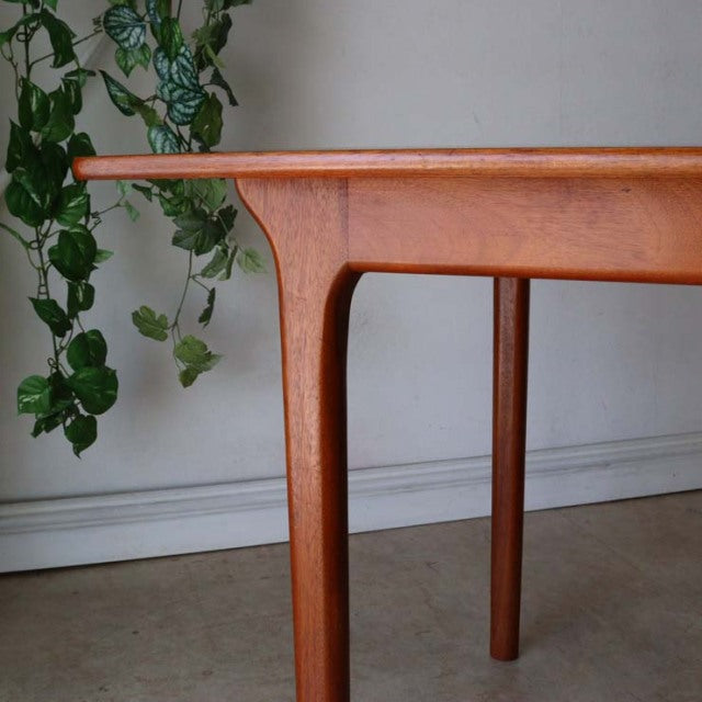 Mid-century British vintage teak dining table corner with smooth rounded edges and tapered legs from McIntosh.