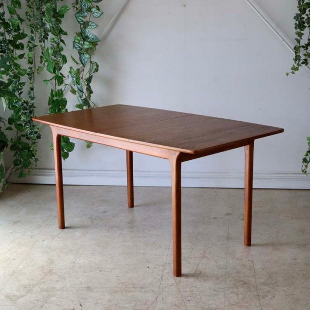 Vintage mid-century British McIntosh teak dining table with rectangular top, slender tapered legs, and smooth wood grain.