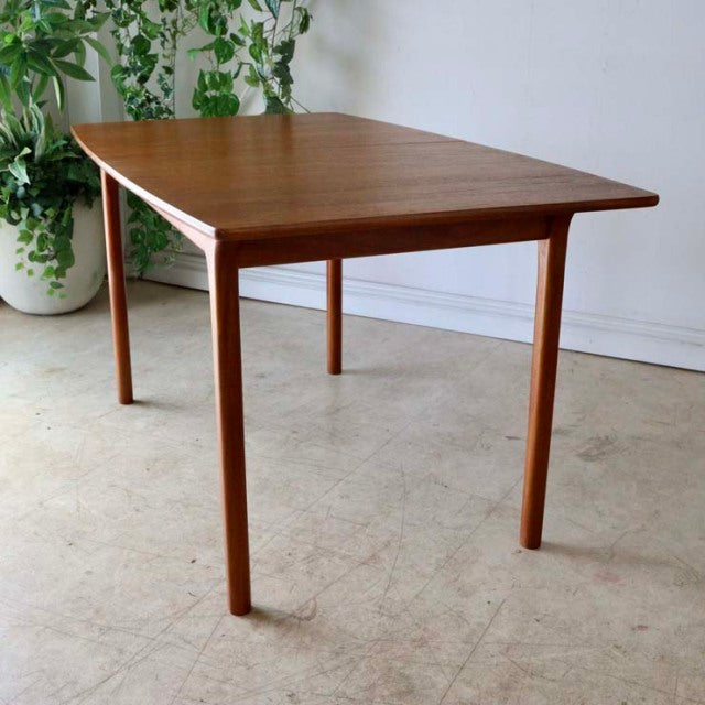 Vintage mid-century British McIntosh teak dining table with slender tapered legs and rich wood grain.