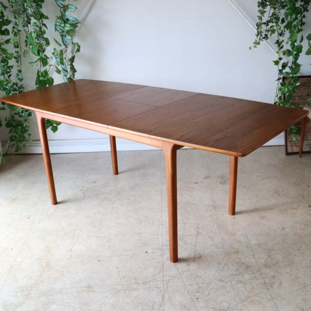 Mid-century British vintage teak dining table by McIntosh with clean lines and tapered legs, showcasing rich wood grain and.