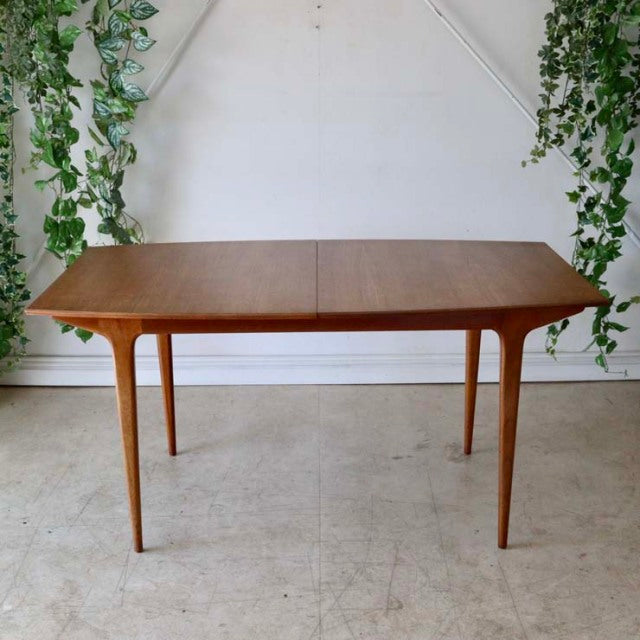 Mid-century British vintage teak dining table by McIntosh with rectangular top and tapered legs, smooth wood grain visible.