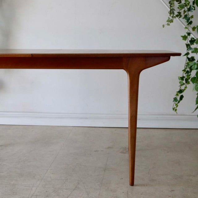 Mid-century British vintage teak dining table with smooth wood grain, tapered legs, and minimalist design from McIntosh.