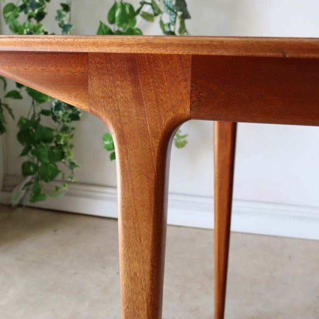 Mid-century British vintage teak dining table with tapered legs and smooth wood grain finish.