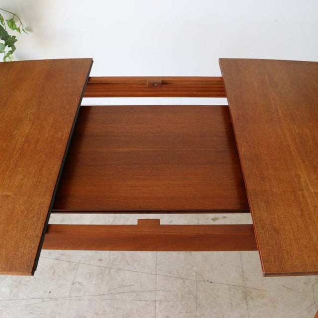 Mid-century British vintage teak dining table in extendable design with rich wood grain and sturdy legs.