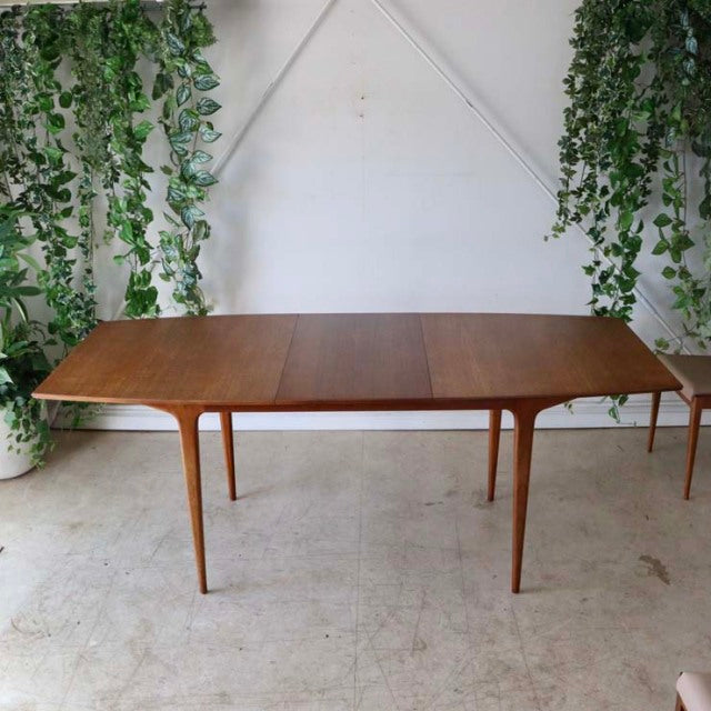 Vintage British mid-century teak dining table by McIntosh with smooth oval top and slender tapered legs.