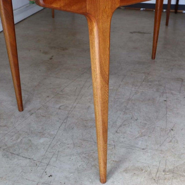 Mid-century British McIntosh teak dining table leg with smooth wood grain and tapered design on concrete floor.