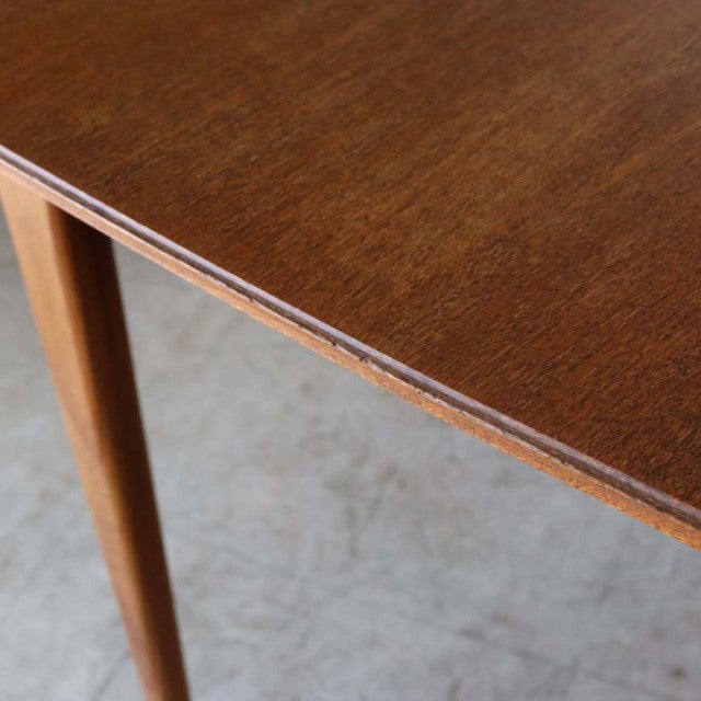 Vintage mid-century McIntosh teak dining table corner with smooth wood grain and tapered British-style legs.