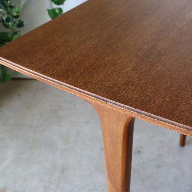 Mid-century British vintage teak dining table corner with smooth wood grain and tapered legs from Denmark style.