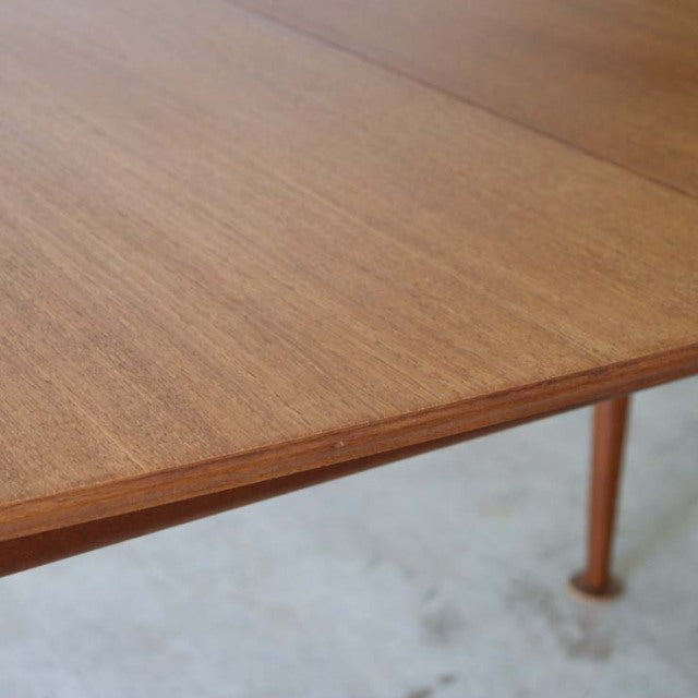 Vintage mid-century teak dining table by McIntosh with smooth wood grain and slender round legs.