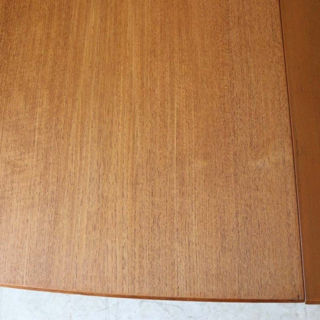 Vintage mid-century McIntosh dining table in warm teak with smooth wood grain and clean rectangular edges.