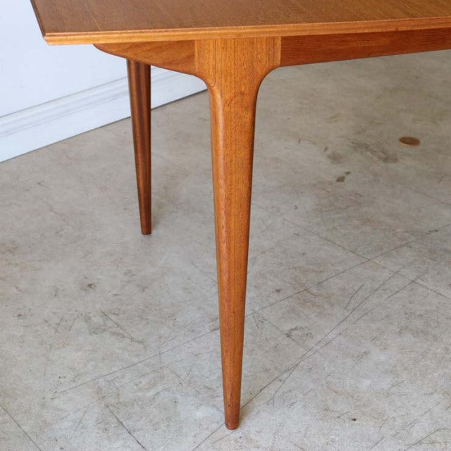 Mid-century British vintage McIntosh dining table with tapered teak legs and smooth wood grain tabletop.