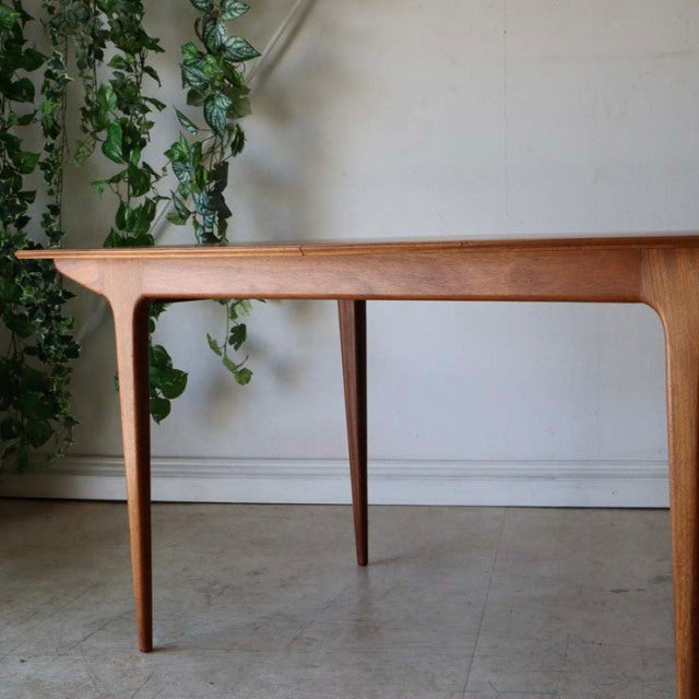 Mid-century British vintage teak dining table by McIntosh with tapered legs and smooth wood grain.