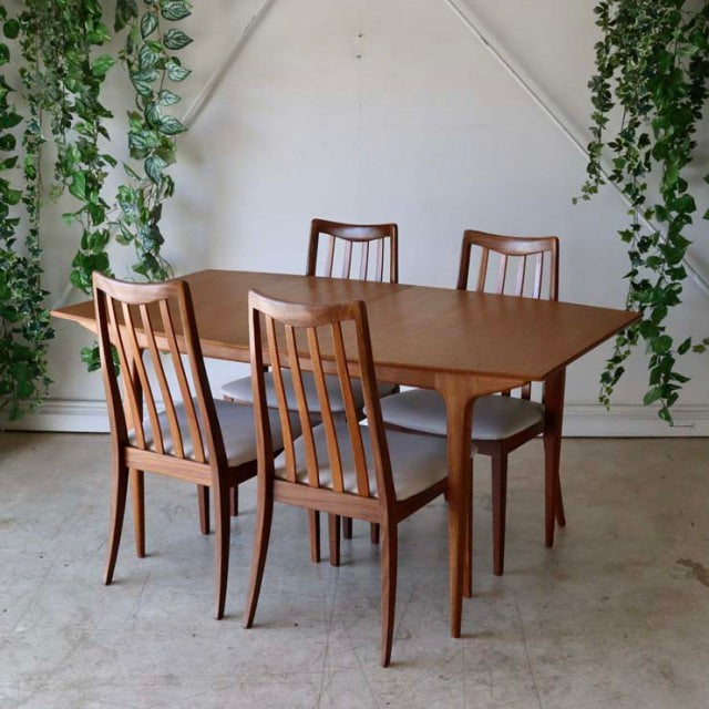 Mid-century British vintage teak dining table with rectangular top and slim, tapered legs surrounded by four matching.