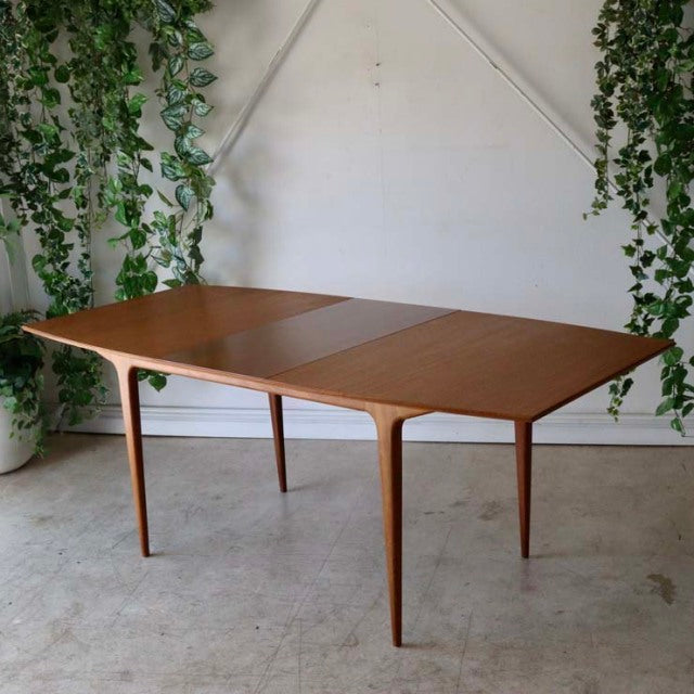 Vintage British mid-century teak dining table by McIntosh with smooth wood grain and elegantly tapered legs.