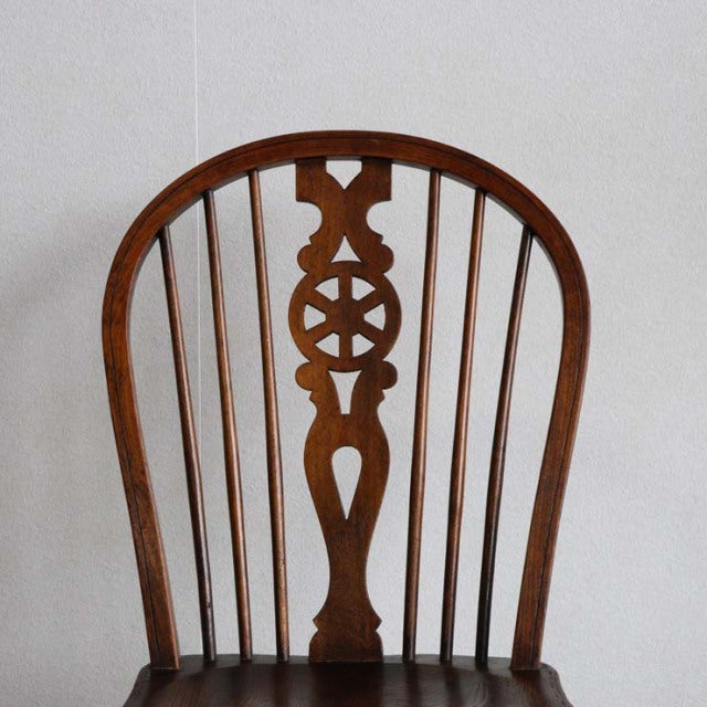 Vintage British teak kitchen chair with curved back, intricate carved central spindle, and slender vertical spindles in.