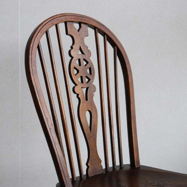 Vintage British mid-century teak kitchen chair with curved backrest and carved central splat, delicate spindle legs.
