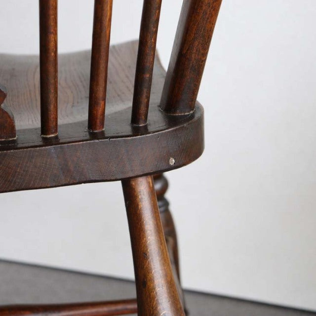 Vintage British mid-century teak kitchen chair with spindle back and tapered legs, rich wood grain.