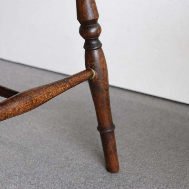 Close-up of vintage teak British mid-century kitchen chair leg with turned details and visible wood grain.
