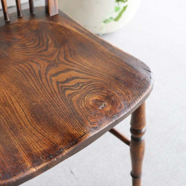 Vintage teak kitchen chair seat close-up showing rich wood grain and turned British mid-century legs.