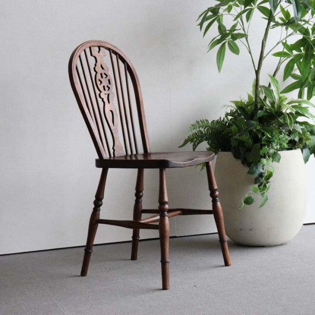 Vintage British teak kitchen chair with mid-century curved backrest and turned legs, detailed wood grain visible.